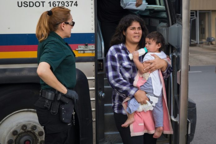 Una mujer baja de un bus con sus bebé luego de ser liberada de un centro de detención en McAllen, Texas, el 17 de junio. © AFP/Archivos Loren ELLIOTT