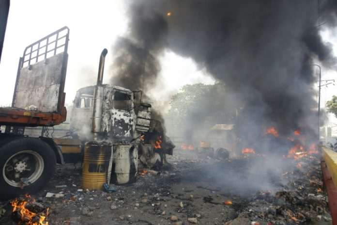 Un hombre vierte gasolina sobre un camión en llamas en la frontera con Venezuela