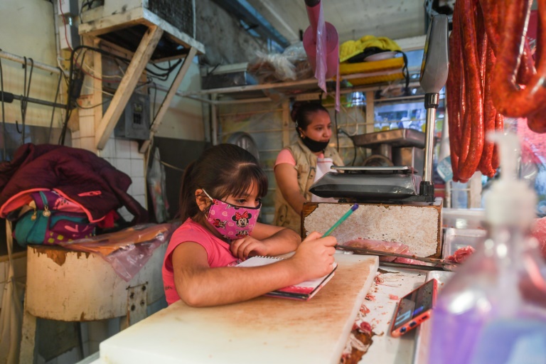La alumna Jade Flores asiste a clase a través de su celular el 25 de agosto de 2020, en la carnicería de su madre en Xochimilco, una de las municipalidades más golpeadas por la pandemia en Ciudad de México © AFP Pedro PARDO